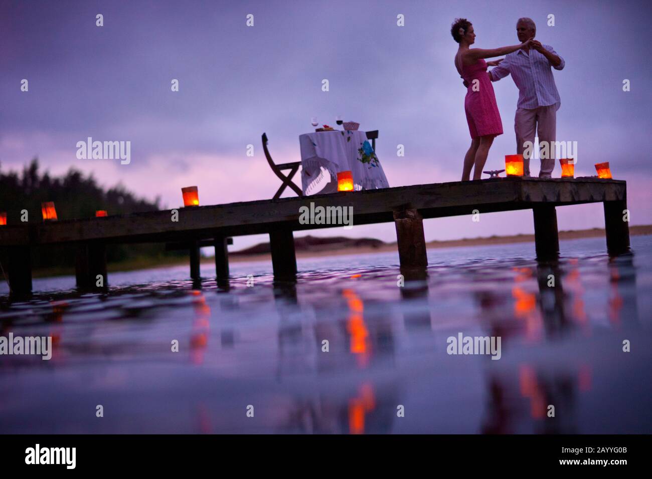 Couple shares a romantic sunset dancing on a pier. Stock Photo