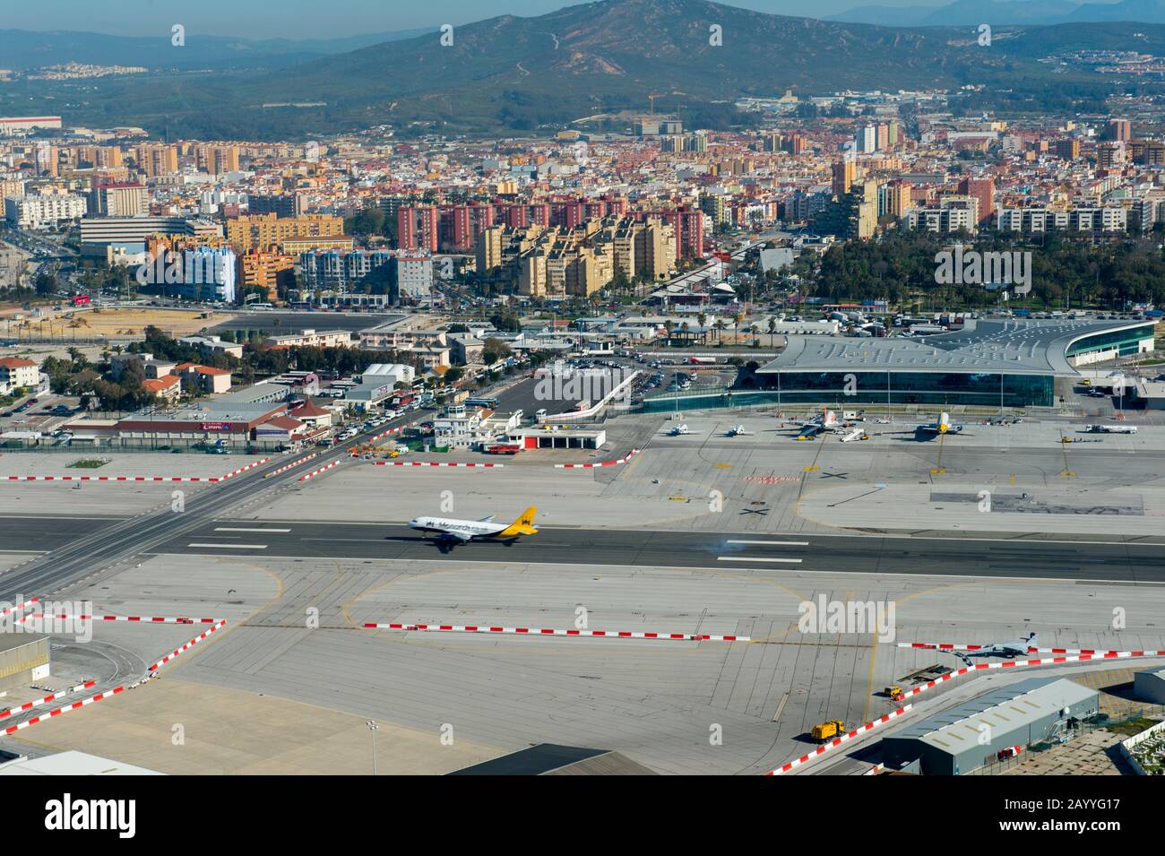 View of the airport with a plane landing and Spain from the World War II tunnels inside of the Rock of Gibraltar, which is a British Overseas Territor Stock Photo