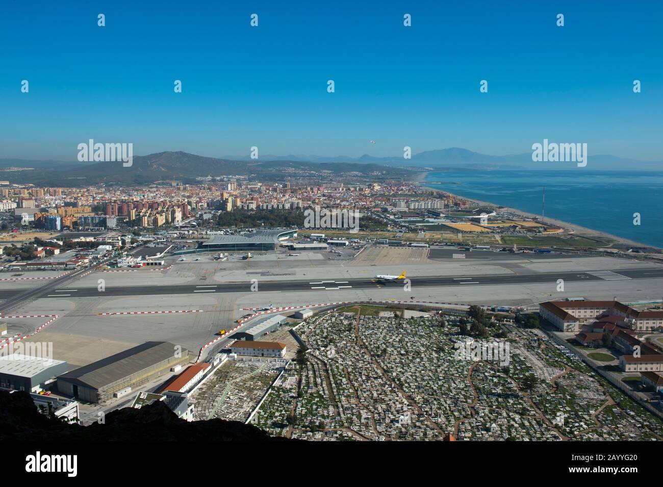 View of the airport with a plane landing and Spain from the World War II tunnels inside of the Rock of Gibraltar, which is a British Overseas Territor Stock Photo