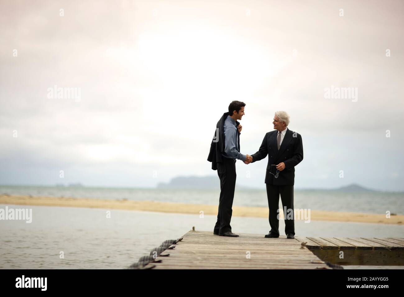 Two businessmen shaking hands on a jetty. Stock Photo