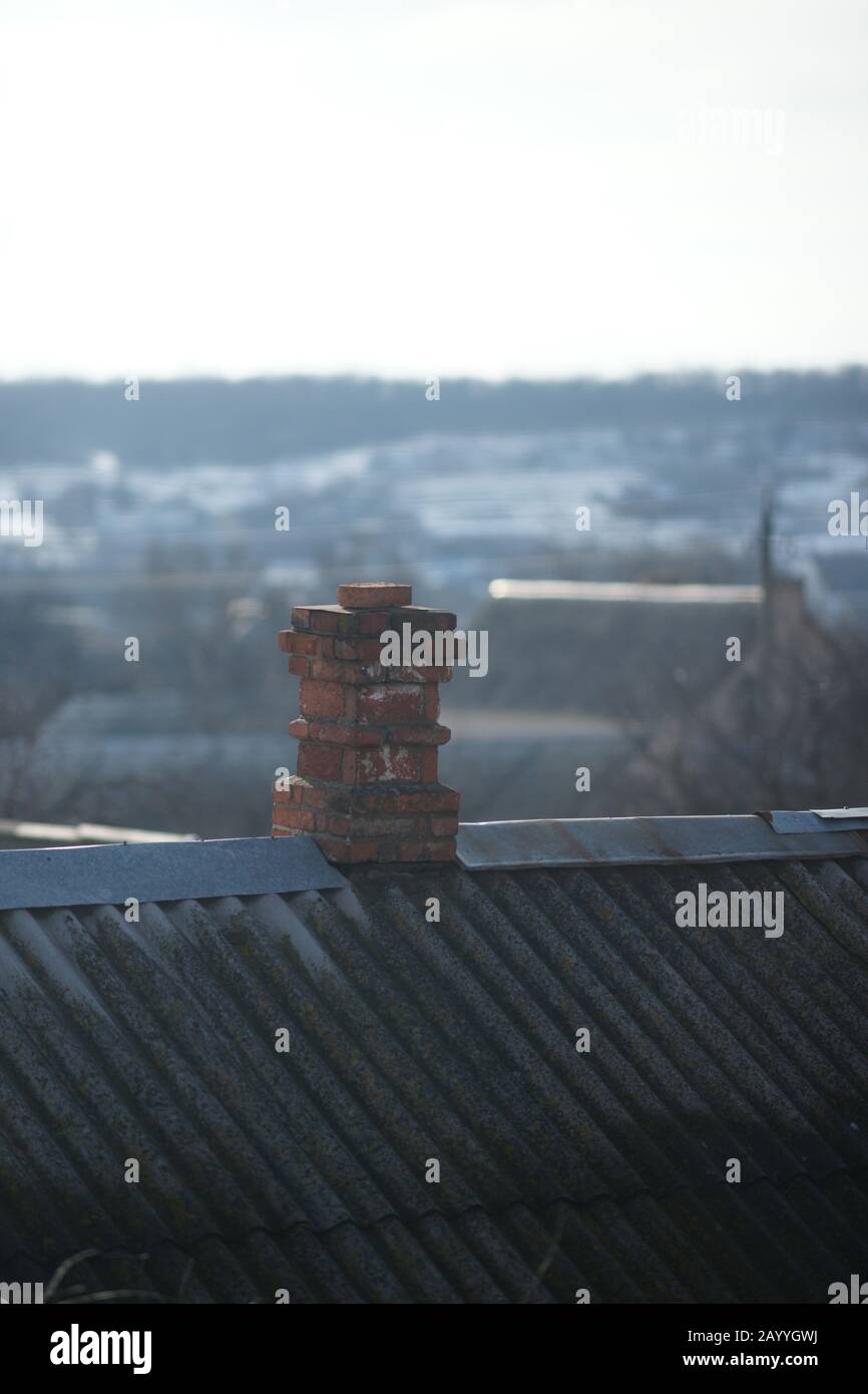 Old chimney in red bricks on the old rural roof. Stock Photo