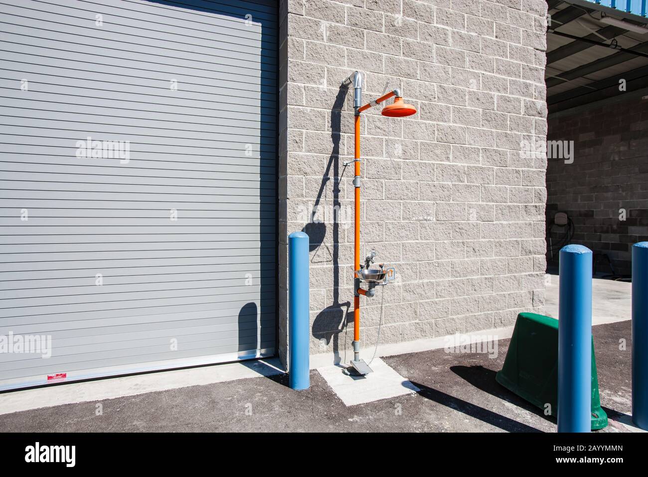 A free standing industrial safety shower with eye wash station stands outside a warehouse facility Stock Photo
