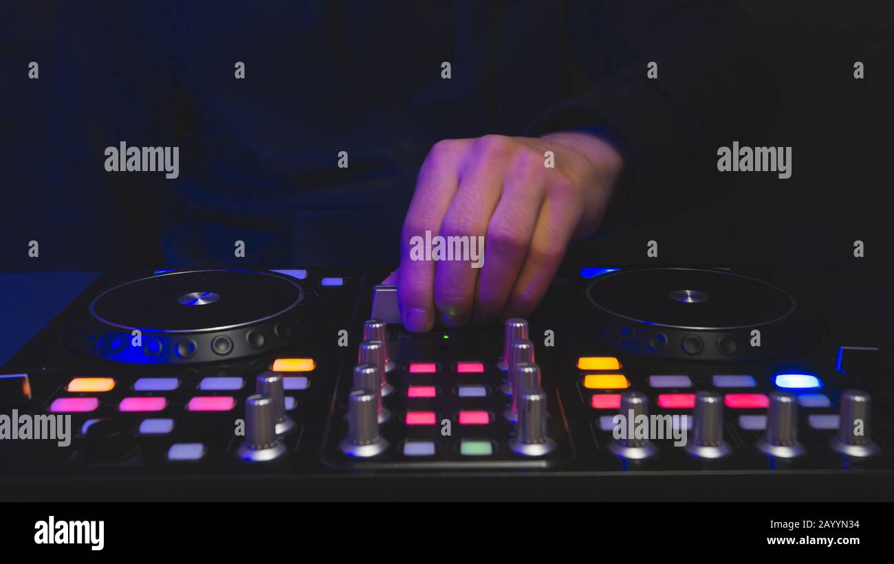 DJ plays music. sound mixer controller with knobs and sliders close up