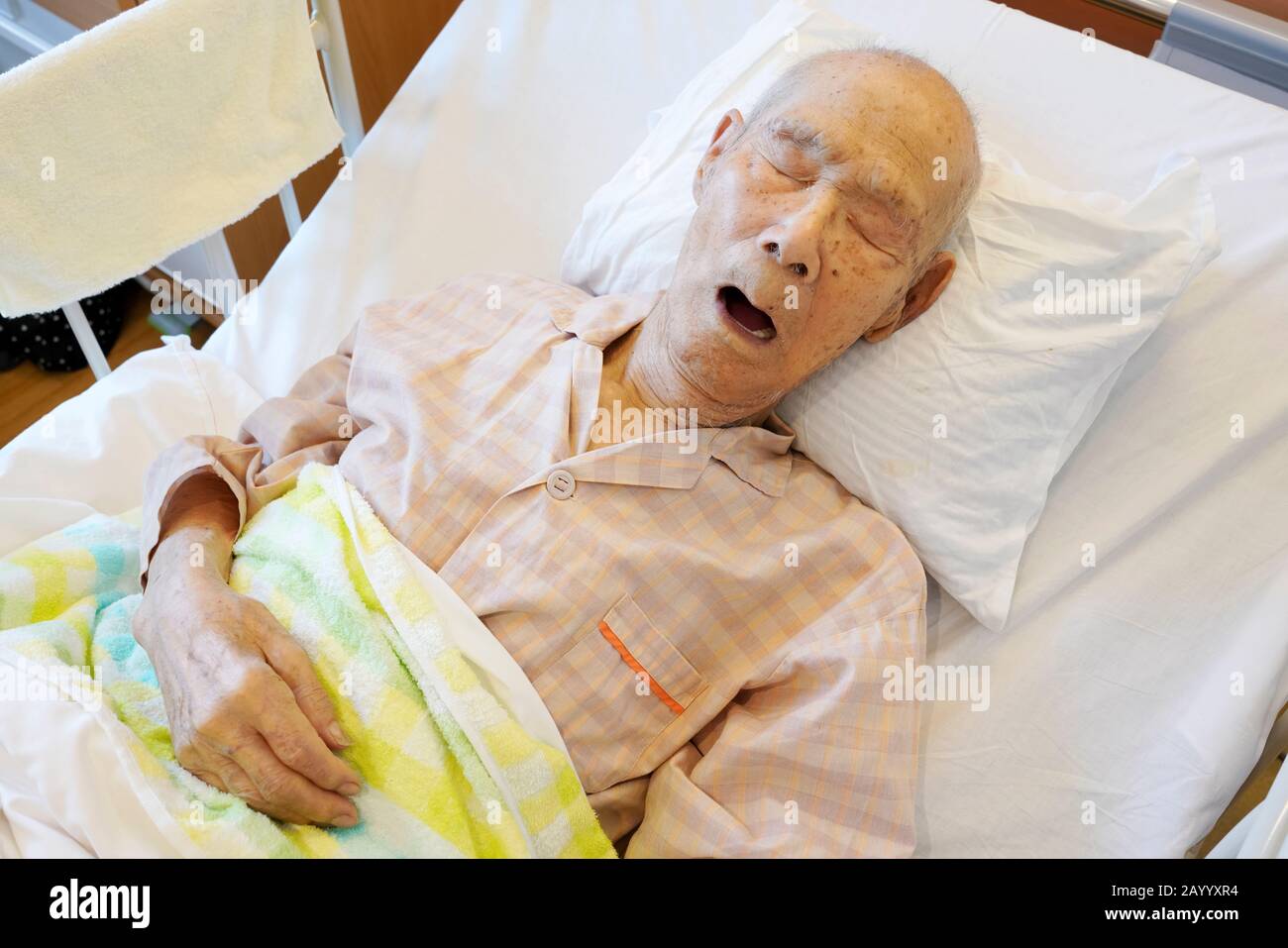 Japanese elderly man patient lying in bed sleeping in hospital Stock Photo