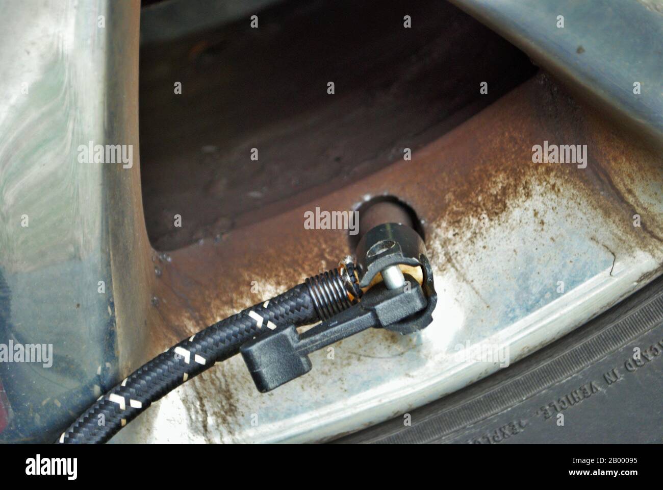 close up of a portable air compressor connected to the valve stem of a car tire Stock Photo