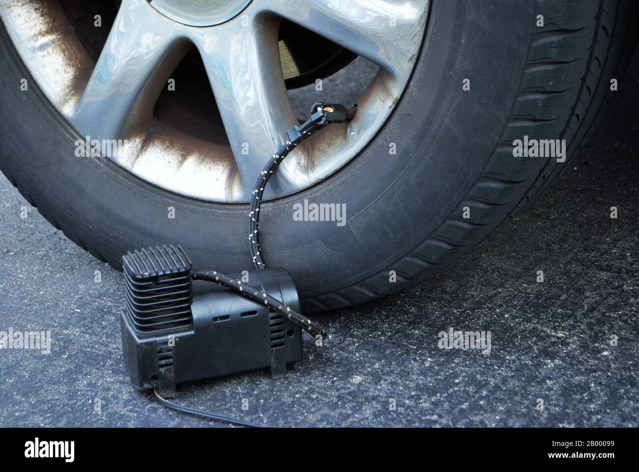 close up of a portable air compressor connected to the valve stem of a car tire Stock Photo