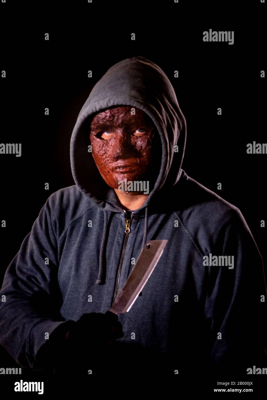 Scary killer in mask and hoodie holding knife Stock Photo