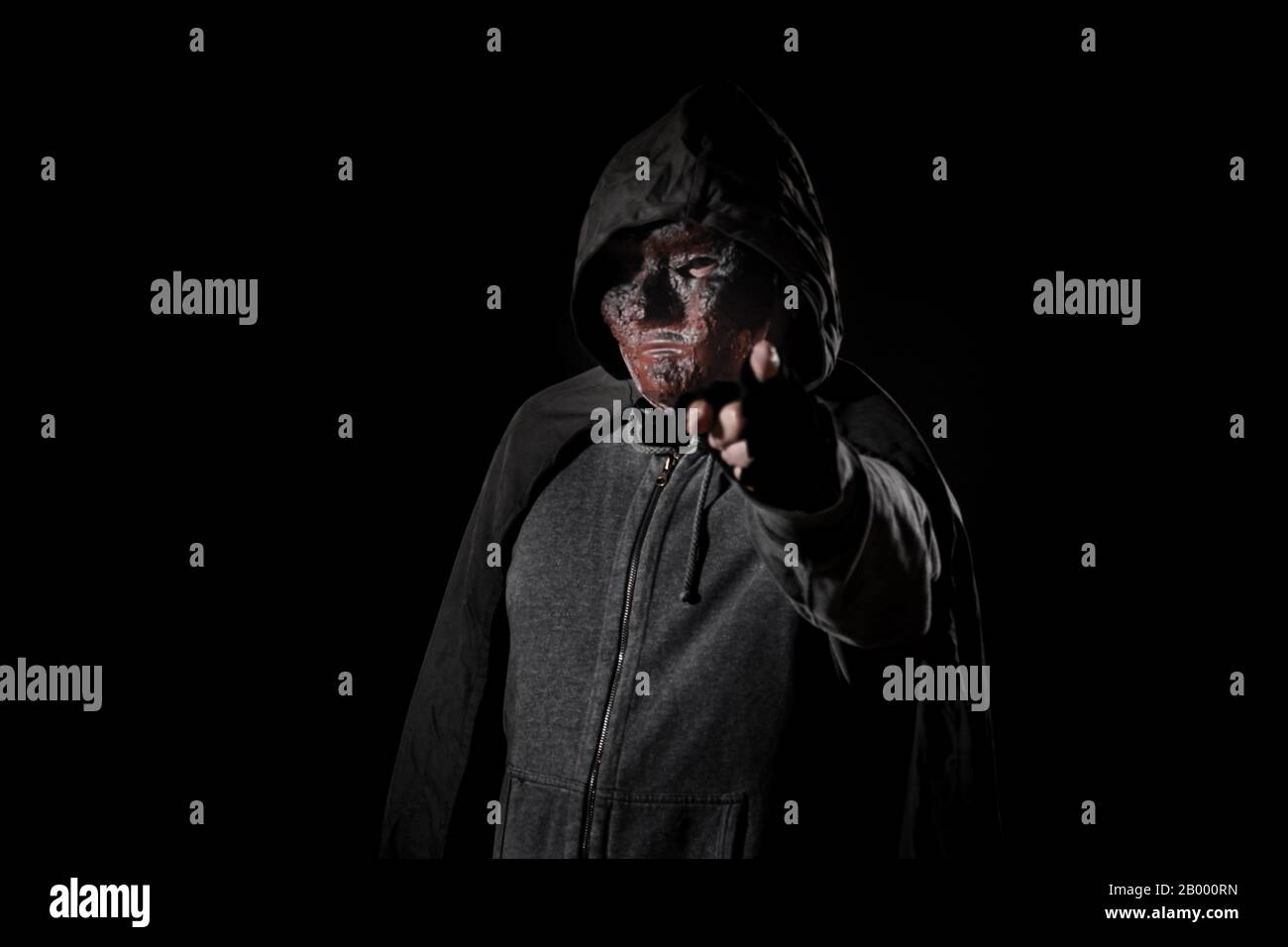 Scary killer in mask and hoodie pointing finger Stock Photo