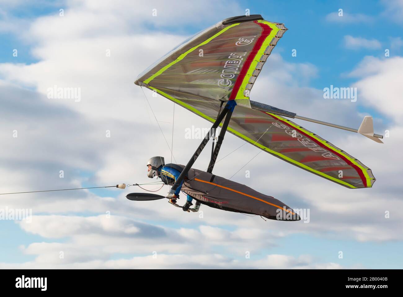 2020-02-09 Byshiv, Ukraine. Hang glider pilot fly on his bright colored wing with bright blue sky on the background. Stock Photo