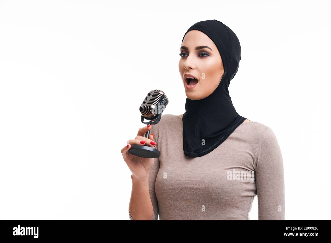 Muslim woman singing with microphone over white background Stock Photo