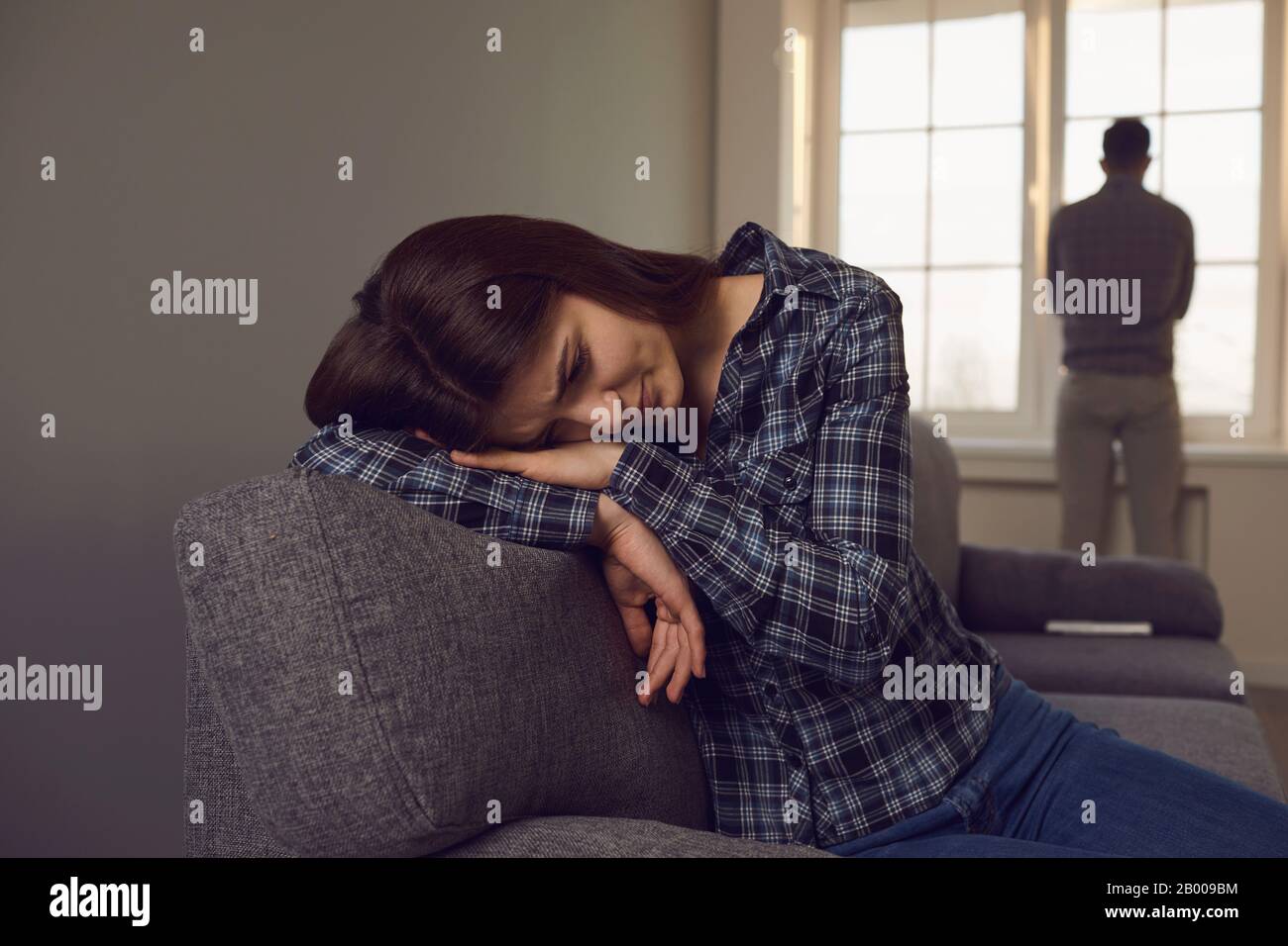 A young couple quarreling while sitting on a sofa in a room. Stock Photo