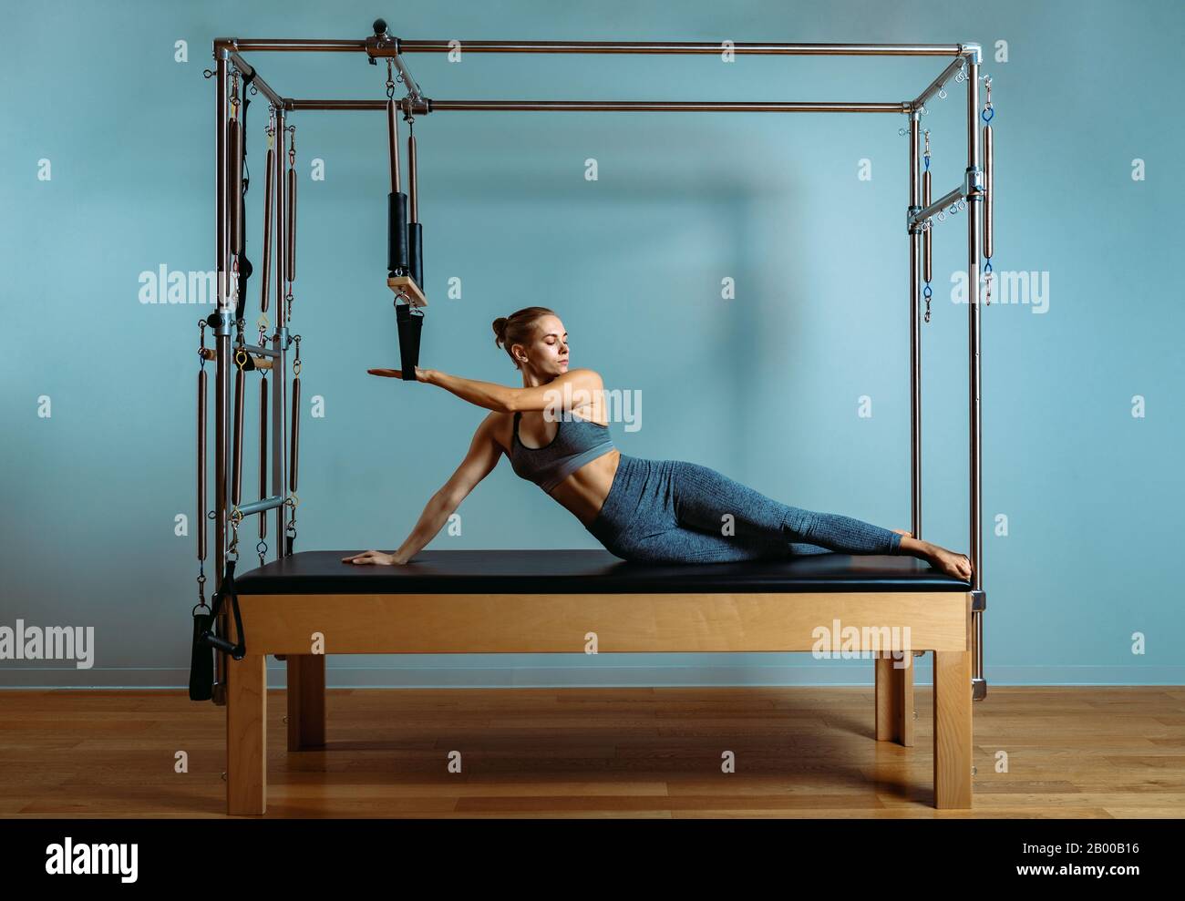 A young girl does Pilates exercises with a bed reformer, barrel machine  tool. Beautiful slim fitness trainer on the background of a reformer doing  var Stock Photo - Alamy