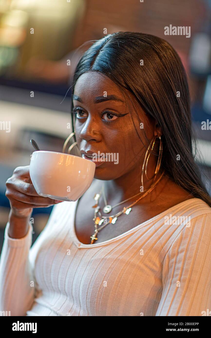 Dark-skinned young woman drinking coffee, Duesseldorf, Germany Stock Photo