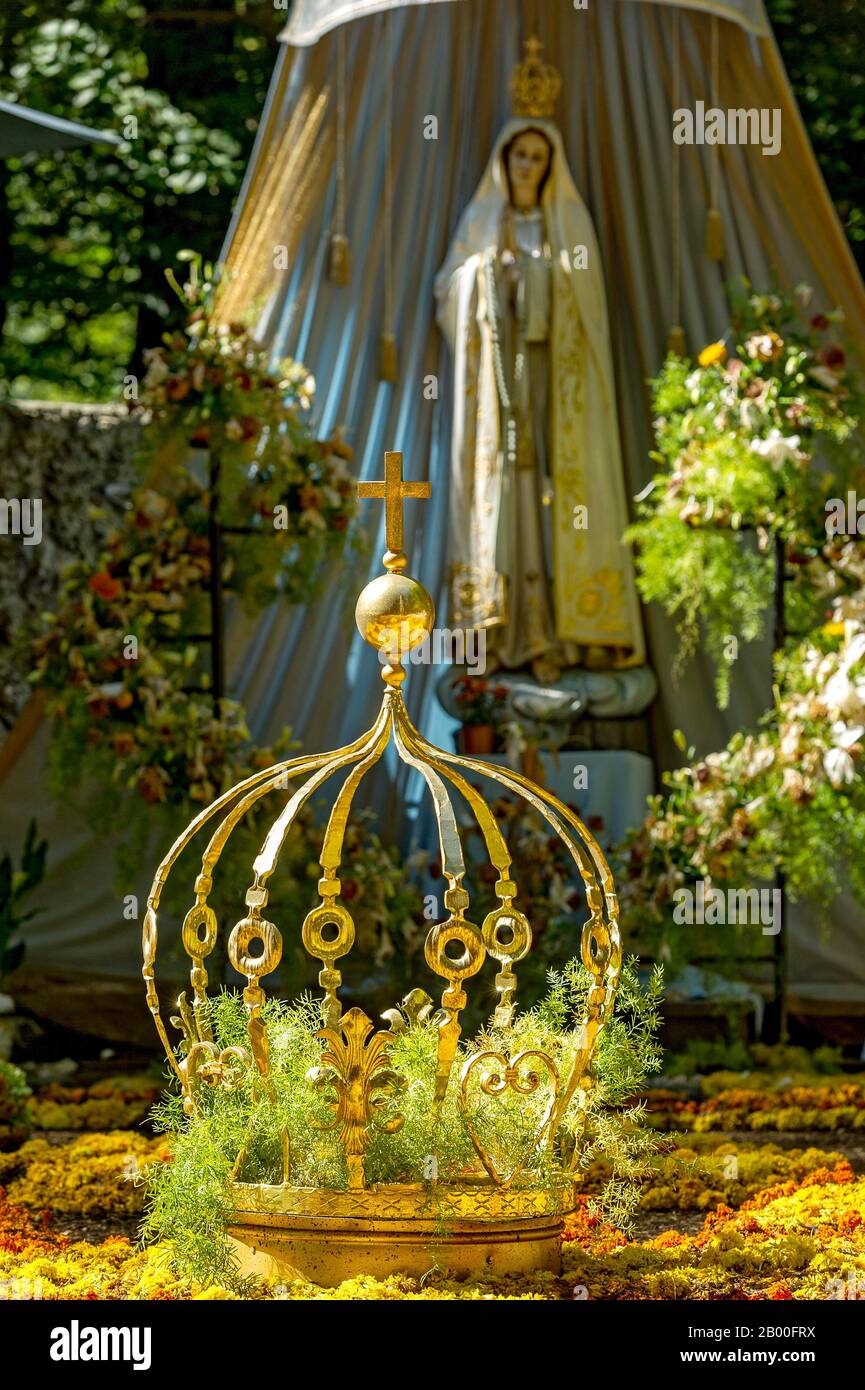 Statue of the Madonna, carpet of flowers with golden crown of the Virgin Mary, grotto of the Virgin Mary in the forest, pilgrimage place Maria Stock Photo