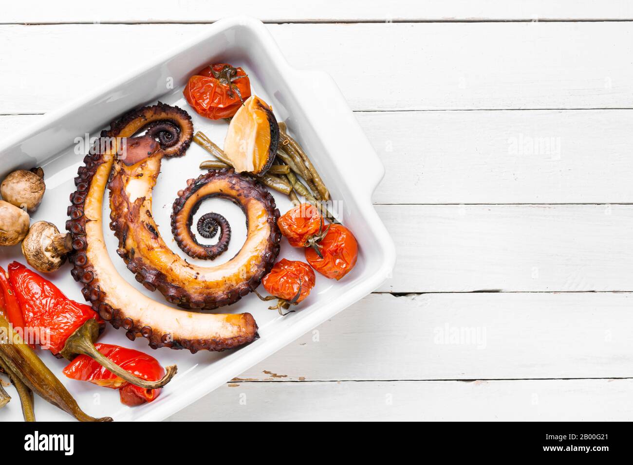 Grilled octopus with roasted vegetables in baking dish Stock Photo