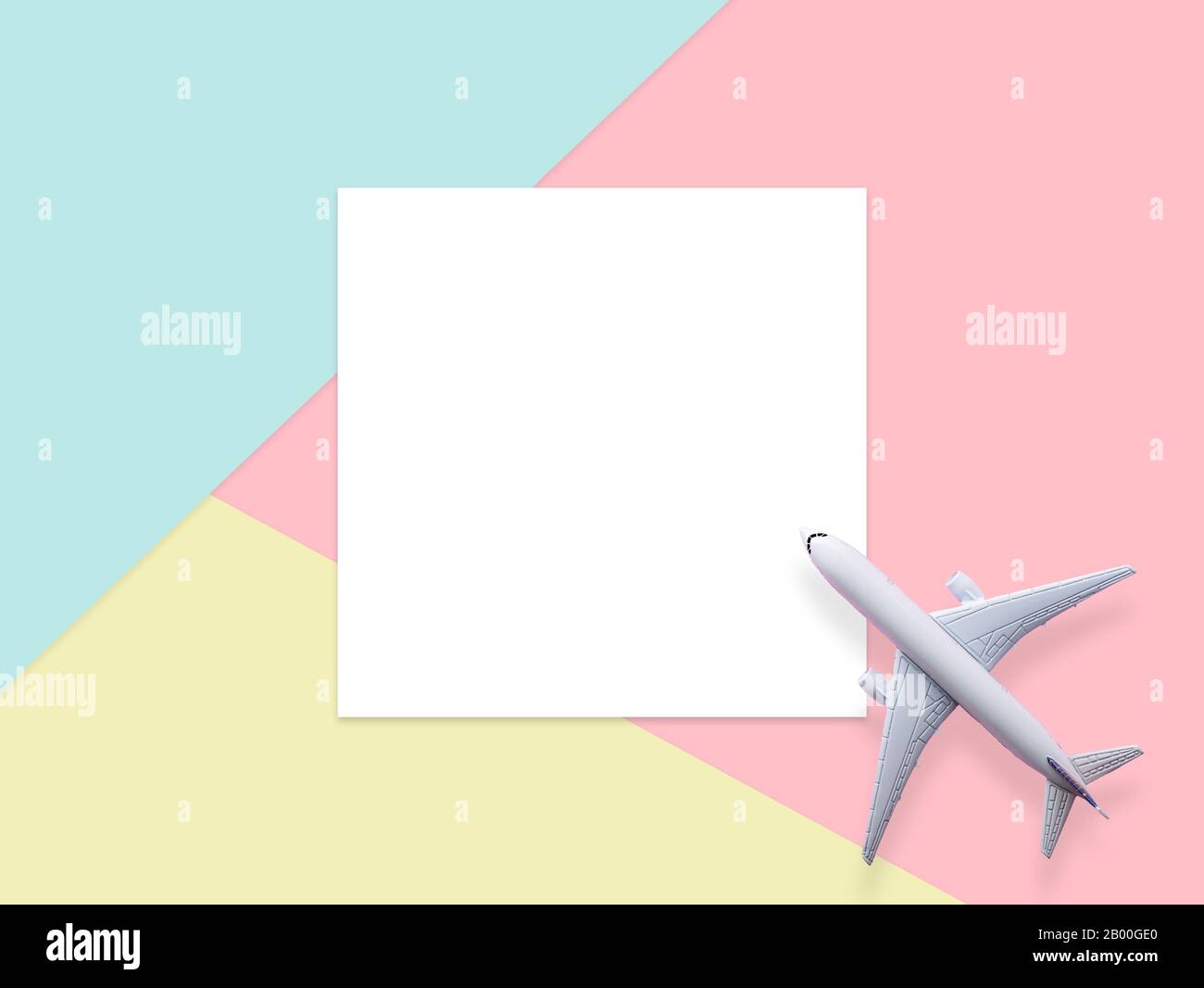 travel by plane concept.simply flat lay design of travel concept with plane on blue , yellow and pink pastel color background with blank white paper f Stock Photo