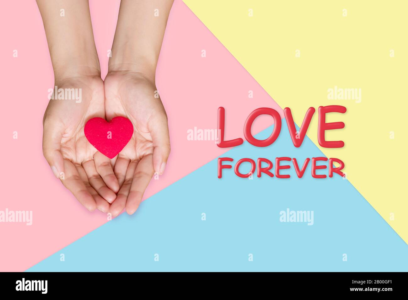 red heart on woman hand with love forever phrase on pastel color background, love concept Stock Photo