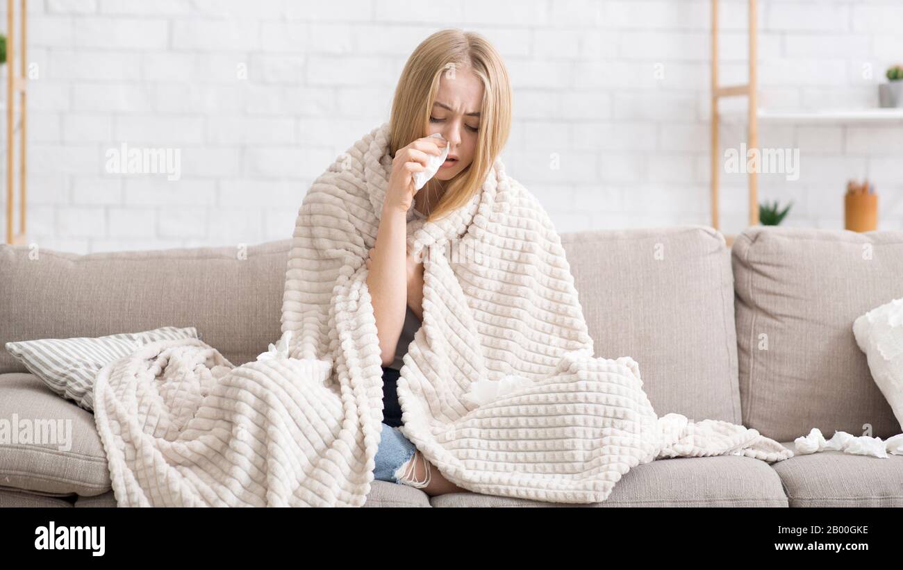 Sick girl wrapped in blanket blowing nose Stock Photo - Alamy
