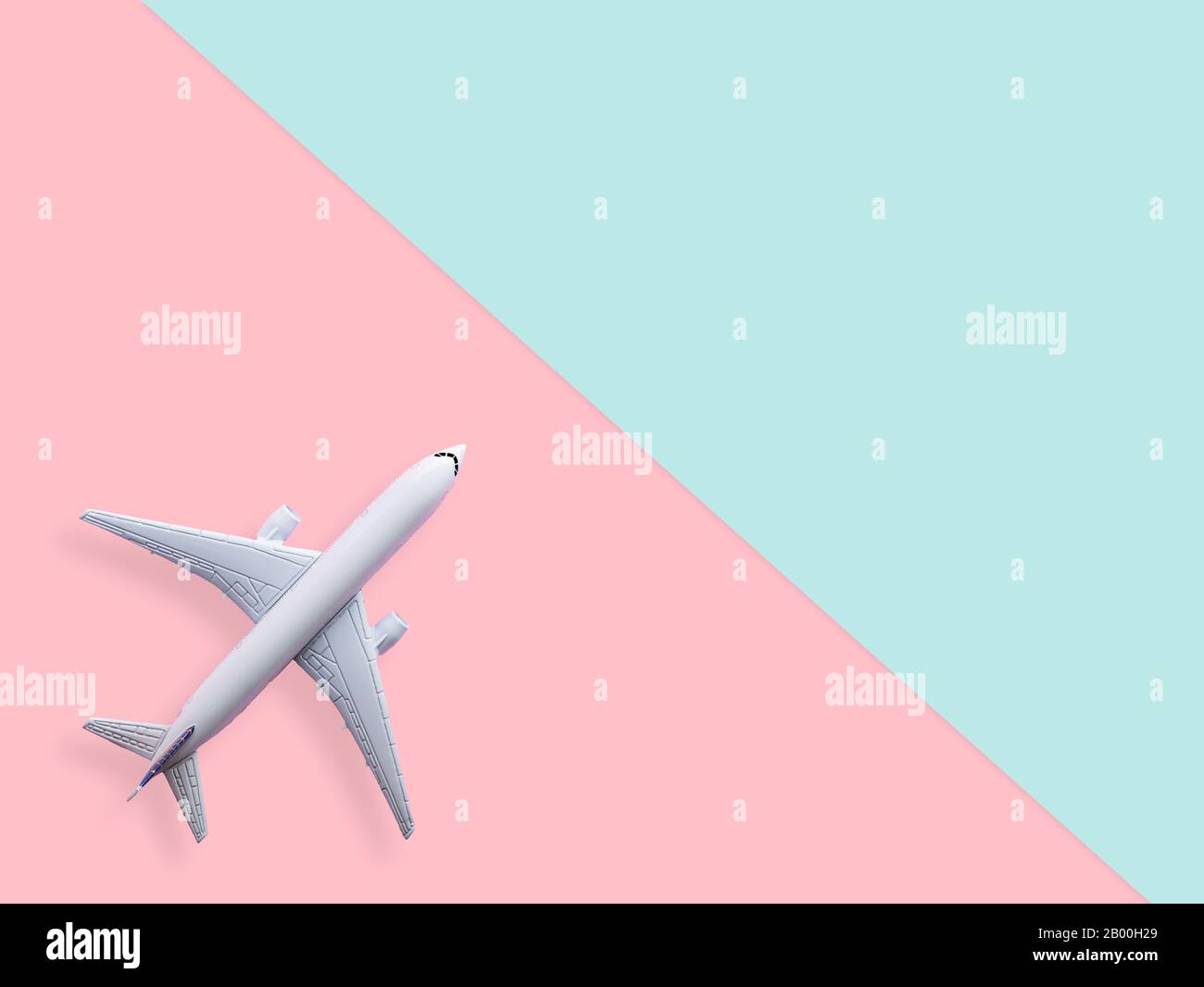 flat lay of white plane model on pastel blue and pink color background with copy space. travel and vacation concept Stock Photo