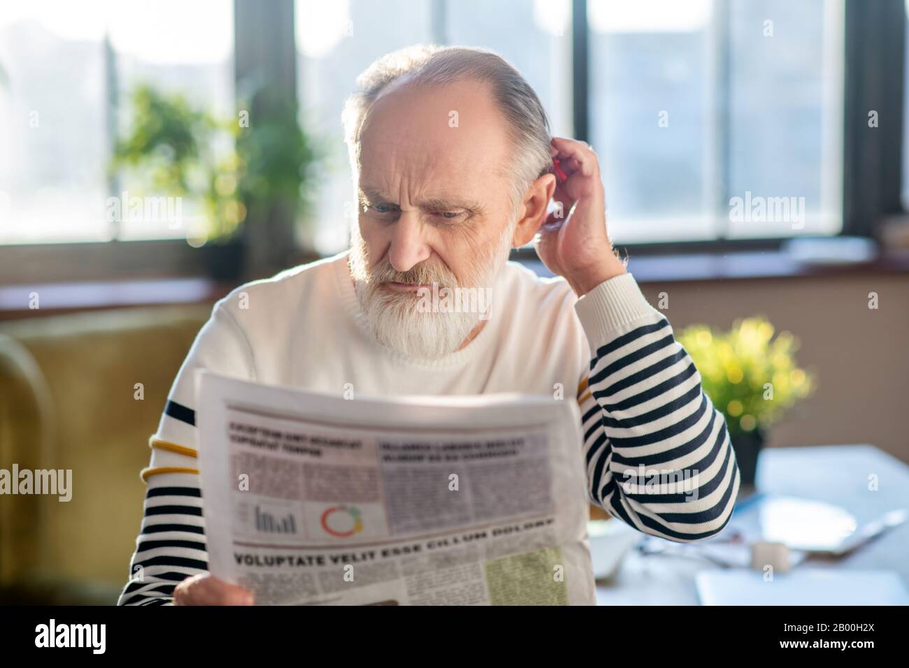 Grey-haired bearded man in reading a newspaper Stock Photo - Alamy