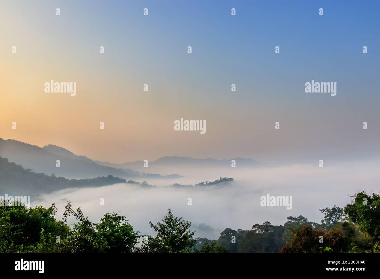 beautiful landscape view on mountain hill top with fog in the morning with orange sunrise. landscape background Stock Photo