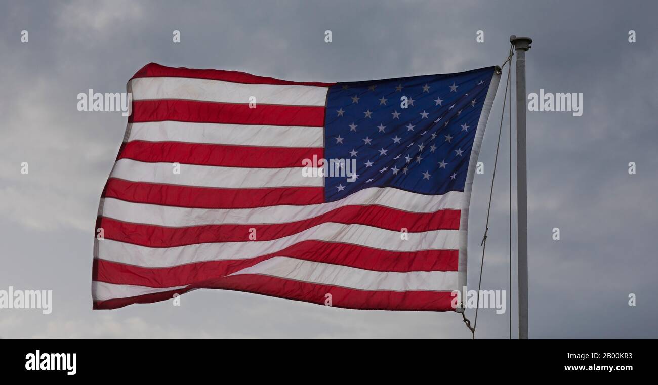 Flag of the United States flying in the breeze with clouds behind Stock Photo