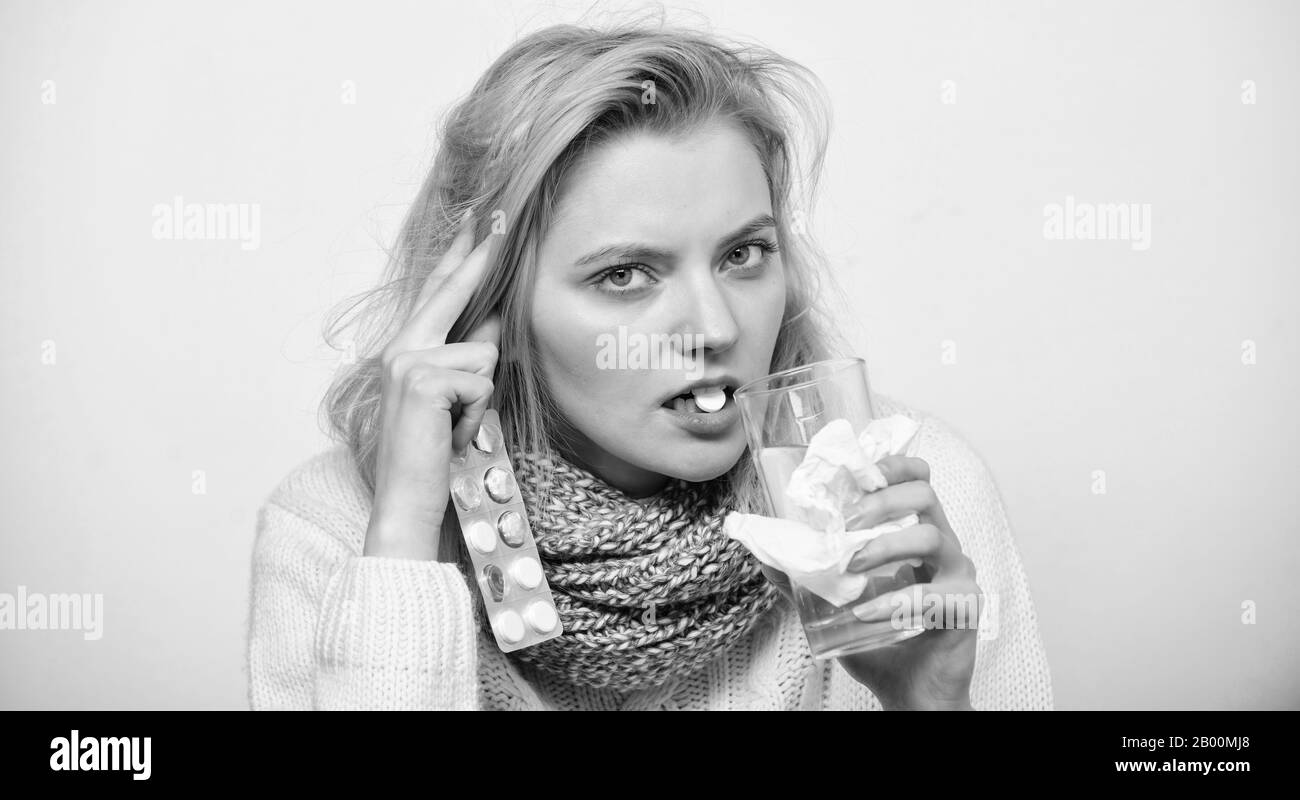 Medicine she can trust. Unhealthy woman holding pills and water glass. Ill woman treating symptoms caused by cold or flu. Cute sick girl taking anti cold pills. Medication and increased fluid intake. Stock Photo