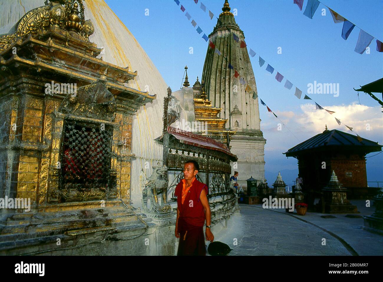Nepal: Monk circumambulates the main stupa, Swayambhunath (Monkey Temple), Kathmandu Valley.  The date of construction of the Svayambhunath stupa, its origins steeped in myth, is unknown. According to the inscriptions on an ancient and damaged stone tablet at Svayambhunath, King Vrishadeva (ca. 400 CE) was the first to build a place of worship on the site. His grandson, King Manadeva I (ca. 464-505) may have made some additions.  The Muslim invasion of 1349 undid all the pious building work, the marauding Muslim warriors dismantling every kafir (infidel) sanctuary that they came across. Stock Photo