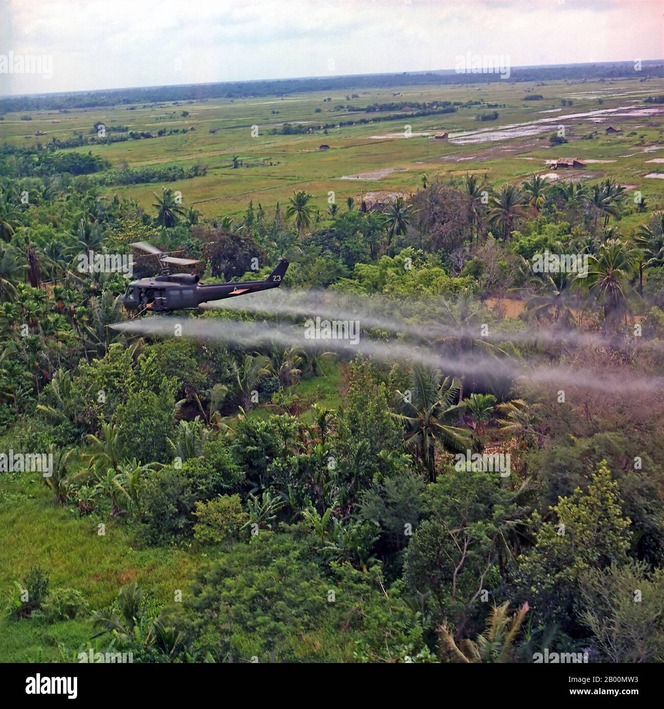 Vietnam: A UH-1D helicopter from the 336th Aviation Company sprays a defoliation agent on a dense jungle area in the Mekong Delta.  During the Vietnam War, between 1962 and 1971, the United States military sprayed 20,000,000 US gallons (80,000,000 L) of chemical herbicides and defoliants in Vietnam, eastern Laos and parts of Cambodia, as part of Operation Ranch Hand. The program's goal was to defoliate forested and rural land, depriving guerrillas of cover; another goal was to induce forced draft urbanization, destroying the ability of peasants to support themselves in the countryside. Stock Photo
