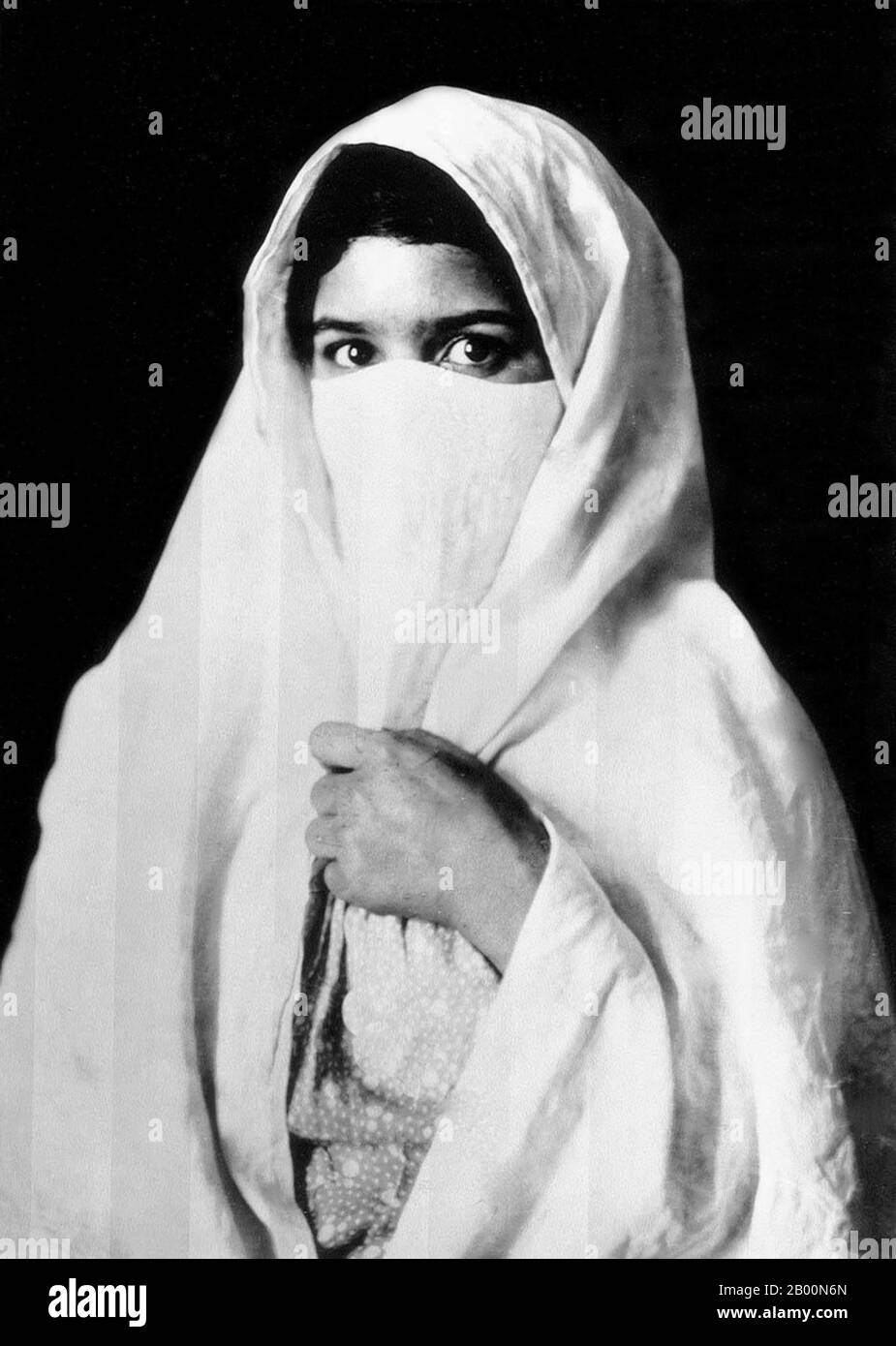 Algeria: Veiled Muslim woman, early 20th century.  Photograph of a veiled woman - presumably an Arab or Bedouin - of Algeria produced as a souvenir for the nascent European tourist market. Stock Photo