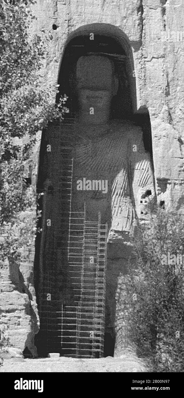 Afghanistan: Bamiyan Buddha in 1979. Photo by Andrew Forbes.  The Buddhas of Bamiyan were two 6th century monumental statues of standing buddhas carved into the side of a cliff in the Bamiyan valley in the Hazarajat region of central Afghanistan, situated 230 km (143 miles) northwest of Kabul at an altitude of 2,500 meters (8,202 ft).  Built in 507 CE, the larger in 554 CE, the statues represented the classic blended style of Gandhara art. The main bodies were hewn directly from the sandstone cliffs, but details were modeled in mud mixed with straw, coated with stucco. Stock Photo