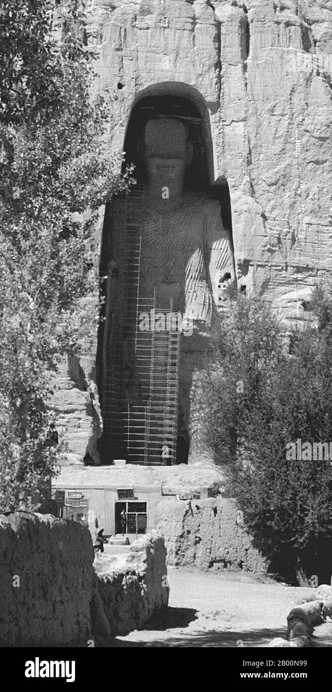 Afghanistan: Bamiyan Buddha in 1979. Photo by Andrew Forbes.  The Buddhas of Bamiyan were two 6th century monumental statues of standing buddhas carved into the side of a cliff in the Bamiyan valley in the Hazarajat region of central Afghanistan, situated 230 km (143 miles) northwest of Kabul at an altitude of 2,500 meters (8,202 ft).  Built in 507 CE, the larger in 554 CE, the statues represented the classic blended style of Gandhara art. The main bodies were hewn directly from the sandstone cliffs, but details were modeled in mud mixed with straw, coated with stucco. Stock Photo