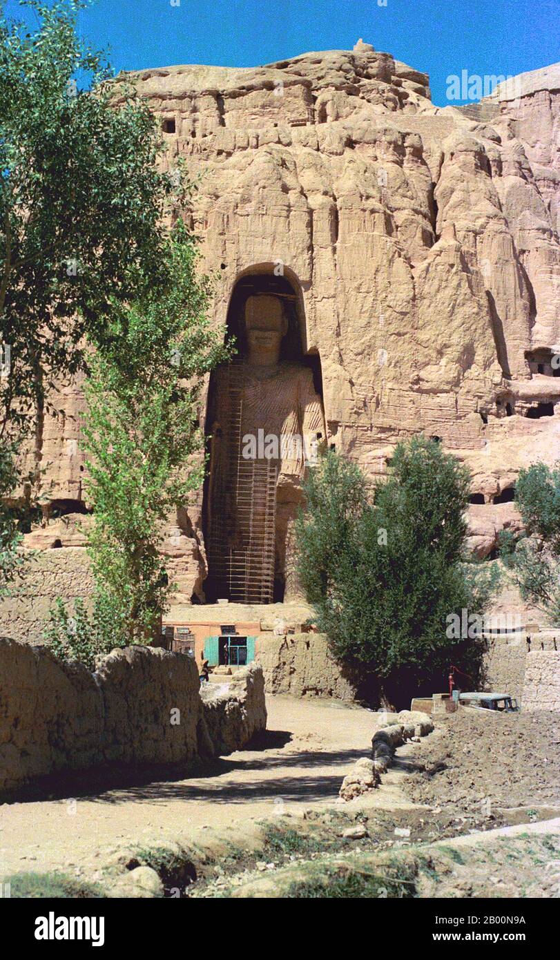 Afghanistan: Bamiyan Buddha in 1979. Photo by Andrew Forbes.  The Buddhas of Bamiyan were two 6th century monumental statues of standing buddhas carved into the side of a cliff in the Bamiyan valley in the Hazarajat region of central Afghanistan, situated 230 km (143 miles) northwest of Kabul at an altitude of 2,500 meters (8,202 ft).  Built in 507 CE, the larger in 554 CE, the statues represented the classic blended style of Gandhara art. The main bodies were hewn directly from the sandstone cliffs, but details were modeled in mud mixed with straw, coated with stucco. Stock Photo