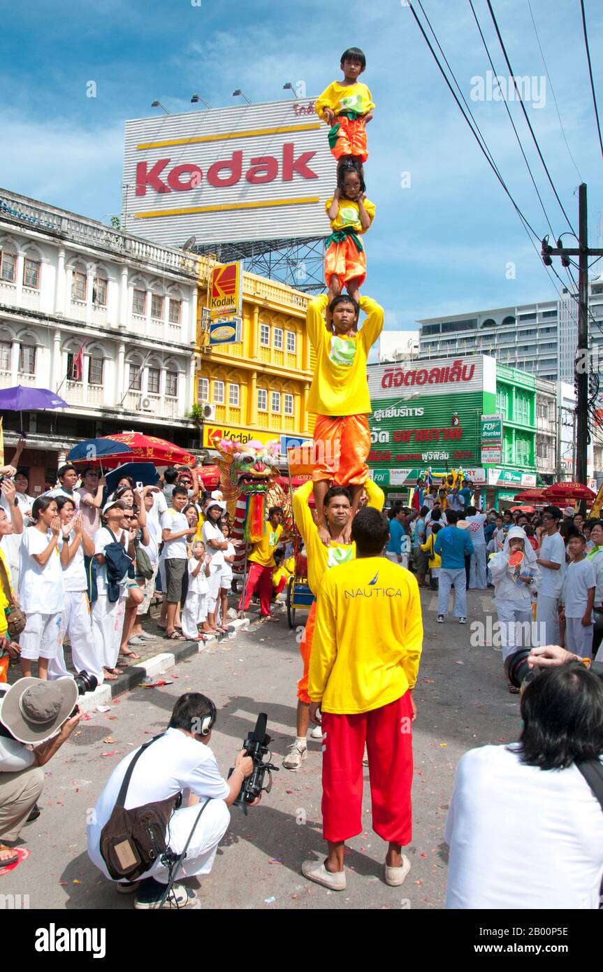 Thailand: Acrobats in a procession through Phuket Town, Phuket Vegetarian Festival.  The Vegetarian Festival is a religious festival annually held on the island of Phuket in southern Thailand. It attracts crowds of spectators because of many of the unusual religious rituals that are performed. Many religious devotees will slash themselves with swords, pierce their cheeks with sharp objects and commit other painful acts. Stock Photo