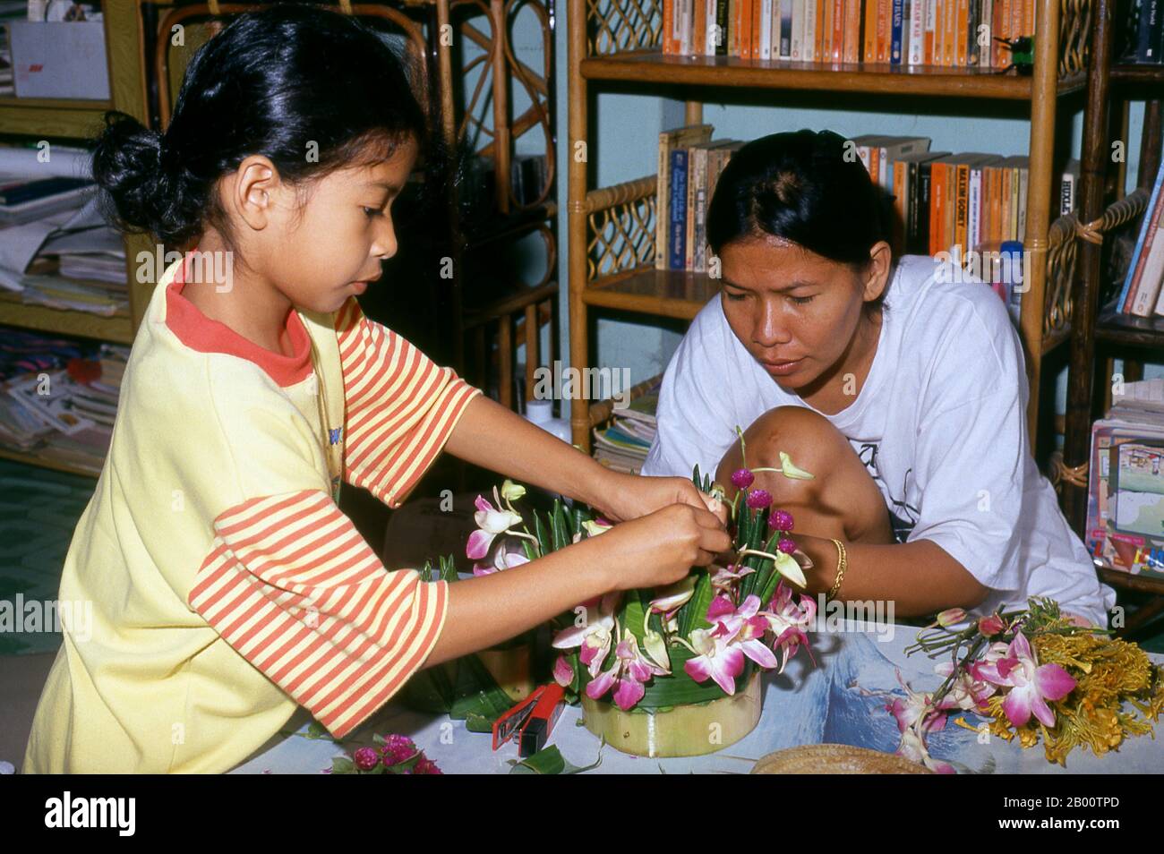 Thailand: Mother and daughter making krathongs, Loy Krathong Festival, Chiang Mai.  Loy Krathong is held annually on the full moon night of the 12th month in the traditional Thai lunar calendar. In northern Thailand this coincides with the Lanna festival known as Yi Peng. Stock Photo
