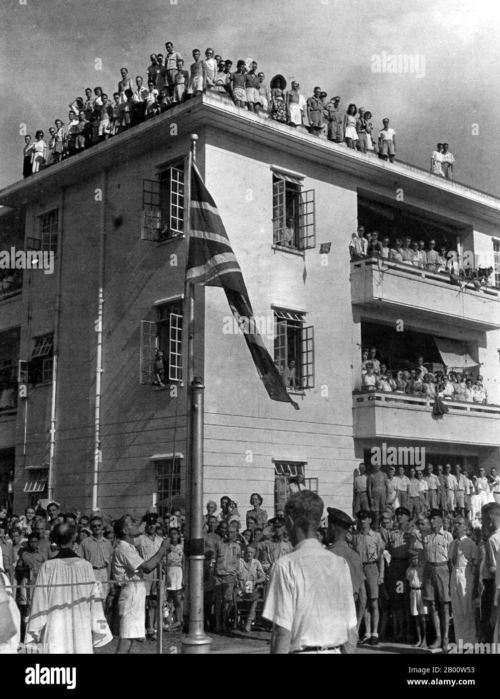 China: The former prisoners of Stanley Camp salute the Union Jack in August, 1945, after 42 months in Japanese captivity.  Stanley Internment Camp was a civilian internment camp in Hong Kong during World War II. Located in Stanley, on the southern end of Hong Kong Island, it was used by the Japanese imperial forces to hold non-Chinese enemy nationals after their victory in the Battle of Hong Kong, a battle in the Pacific campaign of World War II. About 2,800 men, women, and children were held at the camp for 44 months from January 1942 to August 1945 when Japanese forces surrendered. Stock Photo