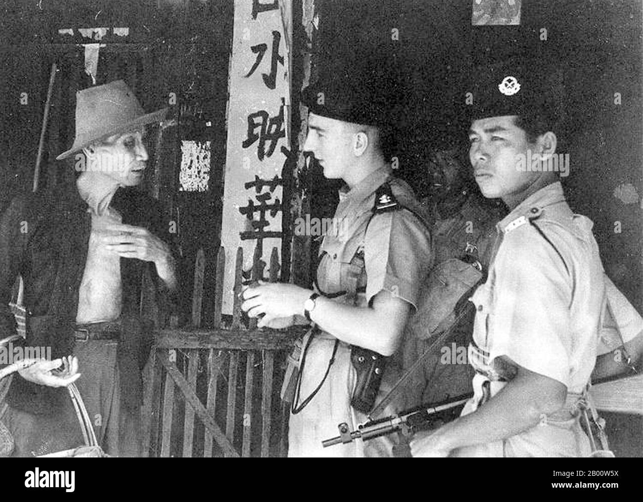 Malaysia: British and Malay military police check the credentials of an elderly Sino-Malay during the 'Emergency', April 1949.  The Malayan Emergency was a guerrilla war fought between Commonwealth armed forces and the Malayan National Liberation Army (MNLA), the military arm of the Malayan Communist Party, from 1948 to 1960. The Malayan Emergency was the colonial government's term for the conflict. The MNLA termed it the Anti-British National Liberation War. Despite the communists' defeat in 1960, communist leader Chin Peng renewed the insurgency in 1967; it would last until 1989. Stock Photo