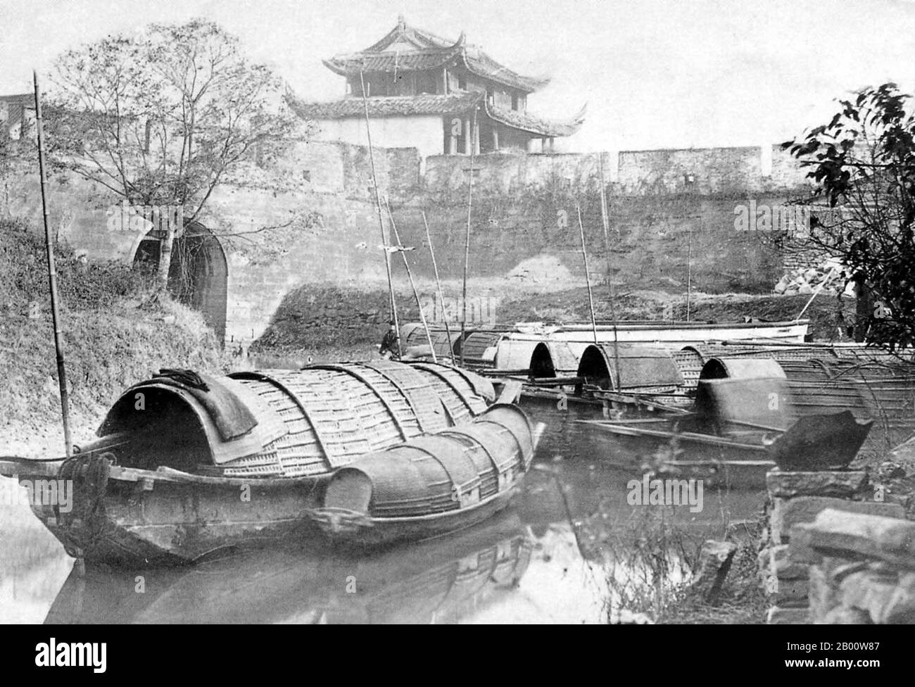 China: Covered boats by Shanghai City Wall, West Gate area, 1890s.  International attention to Shanghai grew in the 19th century due to its economic and trade potential at the Yangtze River. During the First Opium War (1839–1842), British forces temporarily held the city. The war ended with the 1842 Treaty of Nanjing, opening Shanghai and other ports to international trade.  In 1863, the British settlement, located to the south of Suzhou creek (Huangpu district), and the American settlement, to the north of Suzhou creek (Hongkou district), joined in order to form the International Settlement. Stock Photo