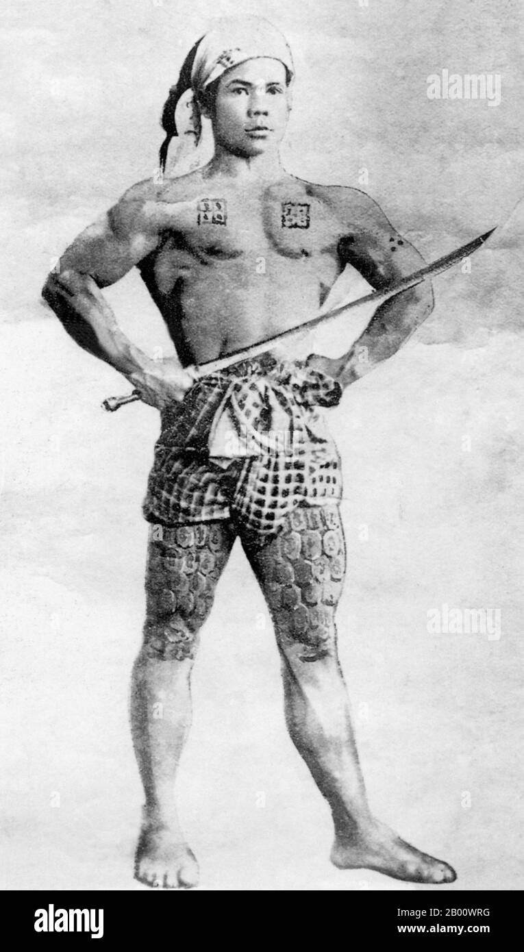 Burma/Myanmar: A tattooed young man poses as a warrior and flexes his muscles for the camera in Mong Un, Shan State, in 1895.  The Shan ethnic group popularized the craft of tattooing in Burma, importing the practice from southern China. Their tattoos had magical or spiritual connotations, similar to the belief in amulets. In Shan culture, a young man was often tattooed from the waist to the knees as a rite of passage and was a sign of virility and maturity. The ritual was performed by the village medicine man, using a long skewer to apply traditional indigo ink or natural vermillion. Stock Photo