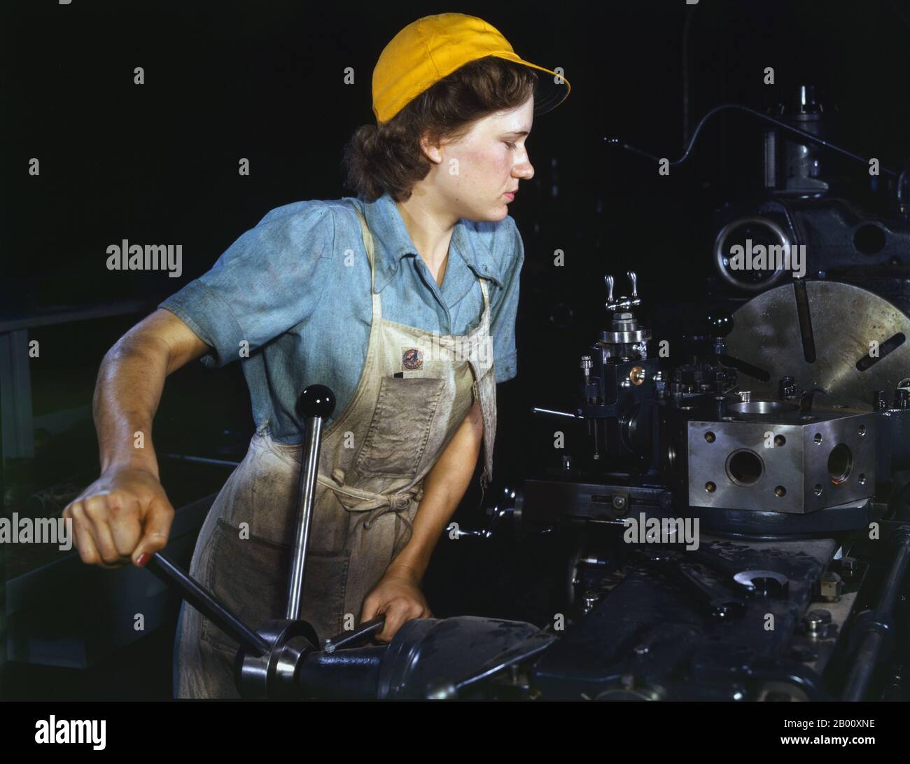 USA: A real life 'Rosie the Riveter' - Turret lathe operator machining parts for transport planes at the Consolidated Aircraft Corporation plant, Fort Worth, Texas. Photo by Howard R. Hollem (-1949), 1942.  'Rosie the Riveter' is a cultural icon of the United States representing the American women who worked in factories during World War II; many worked in manufacturing plants that produced munitions and war supplies. These women sometimes took entirely new jobs replacing the male workers who were in the military. The character is considered a feminist icon in the US and elsewhere. Stock Photo