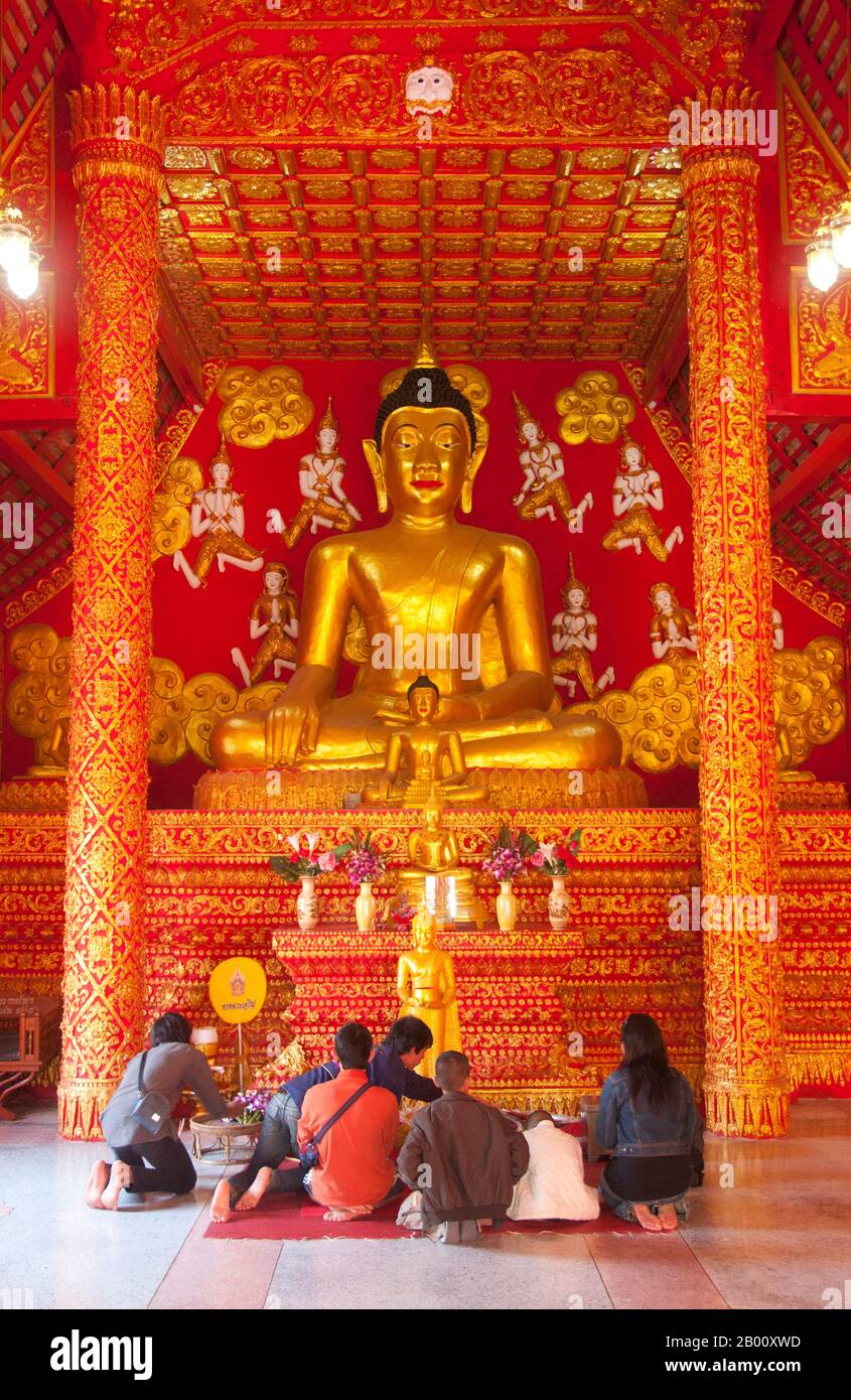 Thailand: Buddha inside a brightly-coloured viharn in the grounds of Wat Phra That Lampang Luang, northern Thailand.  Wat Phra That Lampang Luang (วัดพระธาตุลำปางหลวง), the ‘Temple of the Great Buddha Relic of Lampang’, dates back to the 15th century and is a wooden Lanna-style temple found in the Ko Kha district of Lampang Province. It stands atop an artificial mound, and is surrounded by a high and massive brick wall. The temple itself doubles as a wiang (fortified settlement), and was built as a fortified temple. Stock Photo