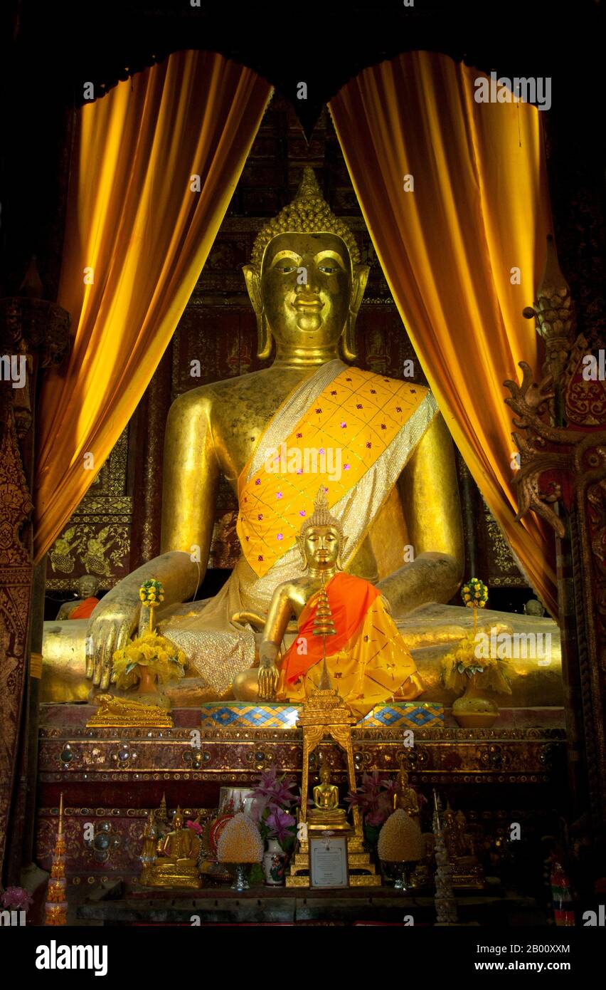 Thailand: Seated Buddha in Viharn Phra Phut, Wat Phra That Lampang Luang, northern Thailand.  Wat Phra That Lampang Luang (วัดพระธาตุลำปางหลวง), the ‘Temple of the Great Buddha Relic of Lampang’, dates back to the 15th century and is a wooden Lanna-style temple found in the Ko Kha district of Lampang Province. It stands atop an artificial mound, and is surrounded by a high and massive brick wall. The temple itself doubles as a wiang (fortified settlement), and was built as a fortified temple. Stock Photo