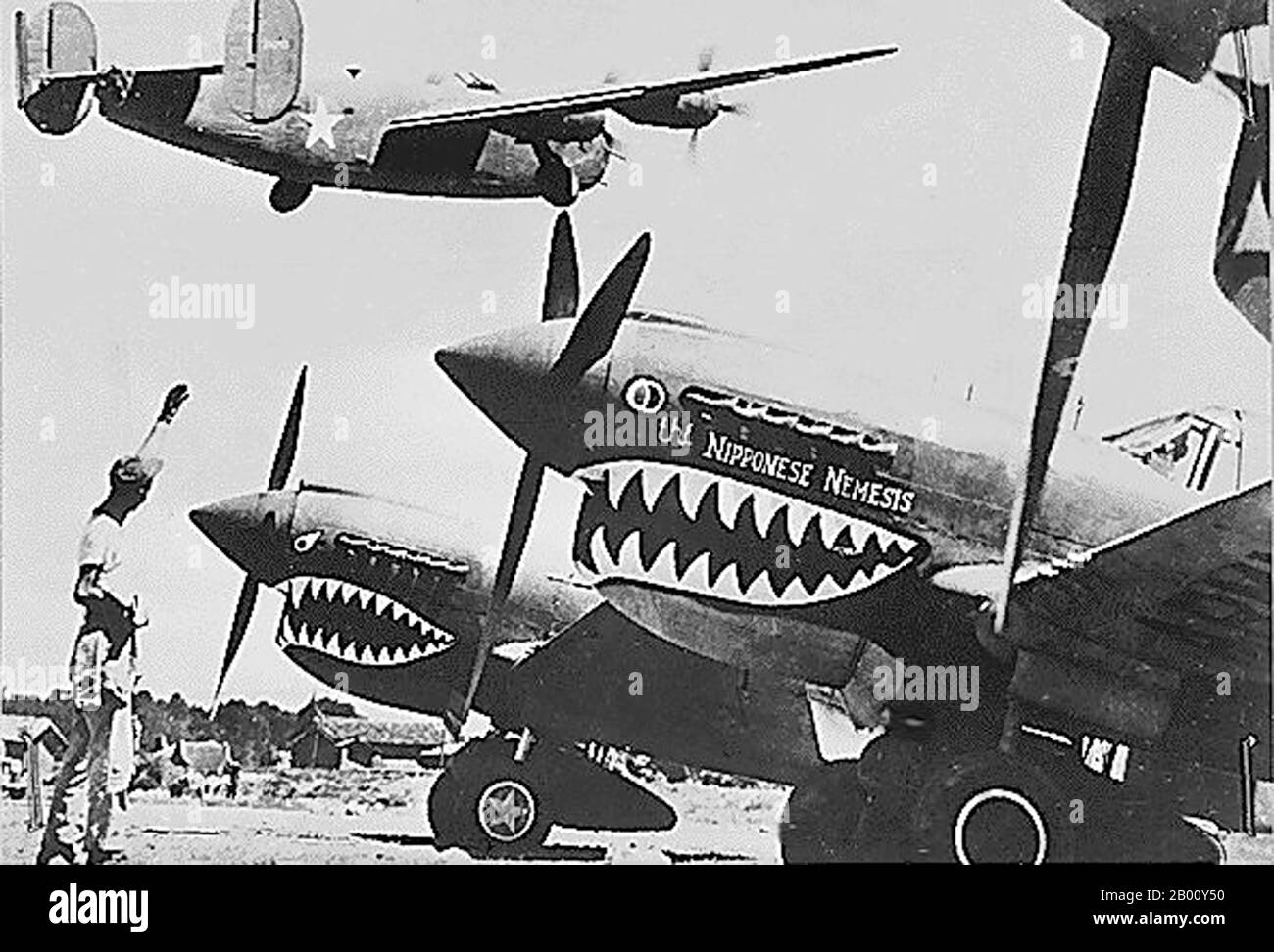 China: American Liberator bomber flies over Flying Tiger  P-40 fighters, Kunming, c. 1942.  Flying Tigers was the popular name of the 1st American Volunteer Group (AVG) of the Chinese Air Force in 1941-1942. The pilots were United States Army (USAAF), Navy (USN), and Marine Corps (USMC) personnel, recruited under Presidential sanction and commanded by Claire Lee Chennault; the ground crew and headquarters staff were likewise mostly recruited from the U.S. military, along with some civilians. The group consisted of three fighter squadrons with about 20 aircraft each. Stock Photo