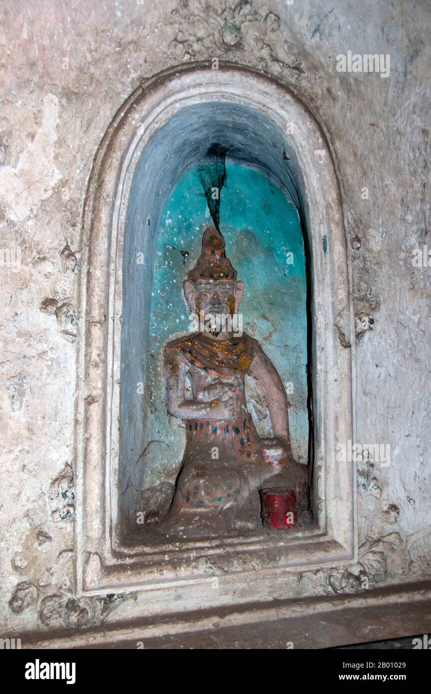 Thailand: Buddha within a niche in Tham Khao Luang, Phetchaburi.  Tham Khao Luang is a large cave consisting of three linked chambers and is distinguished by many hanging stalactites and Buddha images, including a phra non or reclining Buddha. The main bronze image was cast on the orders of King Chulalongkorn (Rama V) and dedicated to his illustrious predecessors, Kings Rama III and Rama IV. There is a natural opening in the ceiling of the second, main chamber, through which daylight streams illuminating the images within. Stock Photo