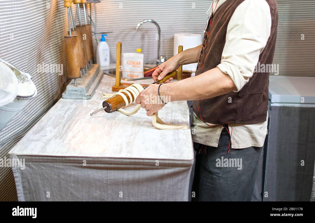 Preparation of the traditional Trdelnik a kind of spit cake made from rolled dough wrapped around a stick, grilled. Stock Photo