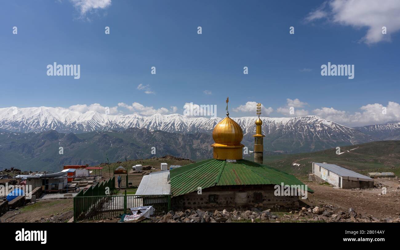 Damavand, Iran - May 23, 2019: base camp of Mount Damavand with mountains and snow and mosque with golden roof. Stock Photo