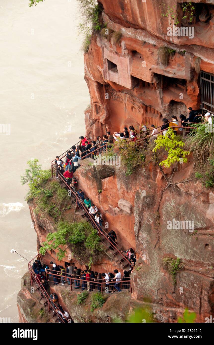 China: Staircase full of visitors waiting to get a sight of Dafo (Giant Buddha) from its feet, Leshan, Sichuan Province.  The Leshan Giant Buddha (Lèshān Dàfó) was built during the Tang Dynasty (618–907 CE). It is carved out of a cliff face that lies at the confluence of the Minjiang, Dadu and Qingyi rivers in the southern part of Sichuan province in China, near the city of Leshan. The stone sculpture faces Mount Emei, with the rivers flowing below his feet. It is the largest carved stone Buddha in the world and at the time of its construction was the tallest statue in the world. Stock Photo