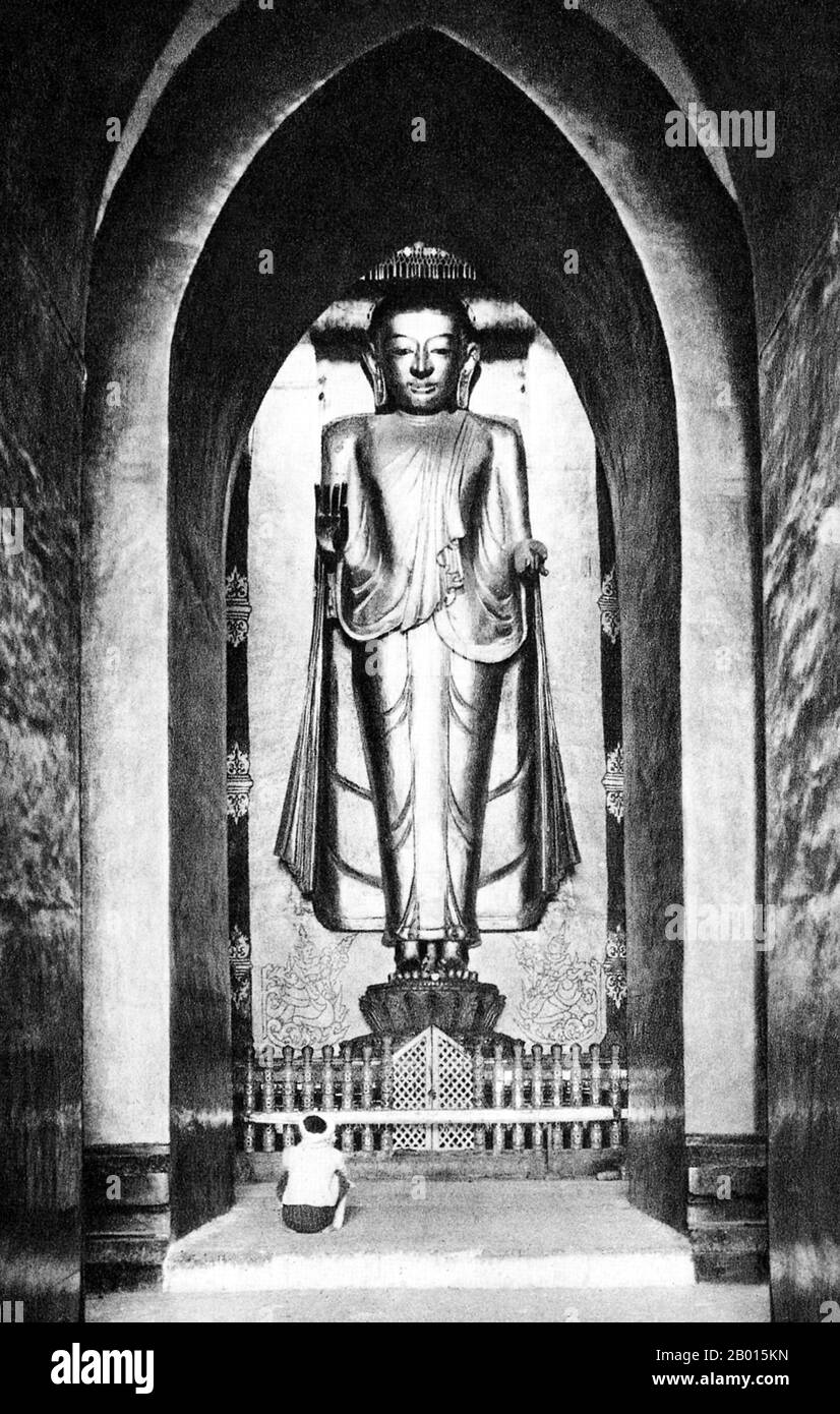Burma/Myanmar: A towering Buddha image in the Ananda temple in Bagan, Upper Burma, c. 1920s.  Perhaps the highest revered temple in Bagan, the Ananda Pagoda was built in 1105 CE during the reign of King Kyanzittha (1084–1113) of the Bagan Dynasty. It is one of four surviving original temples of Bagan (also called Pagan). The temple layout is in a cruciform with several terraces leading to a small pagoda at the top covered by an umbrella (‘hti’).  The Buddhist temple houses four standing Buddhas—facing east, north, west and south, and is a fusion of Mon and adopted Indian style architecture. Stock Photo