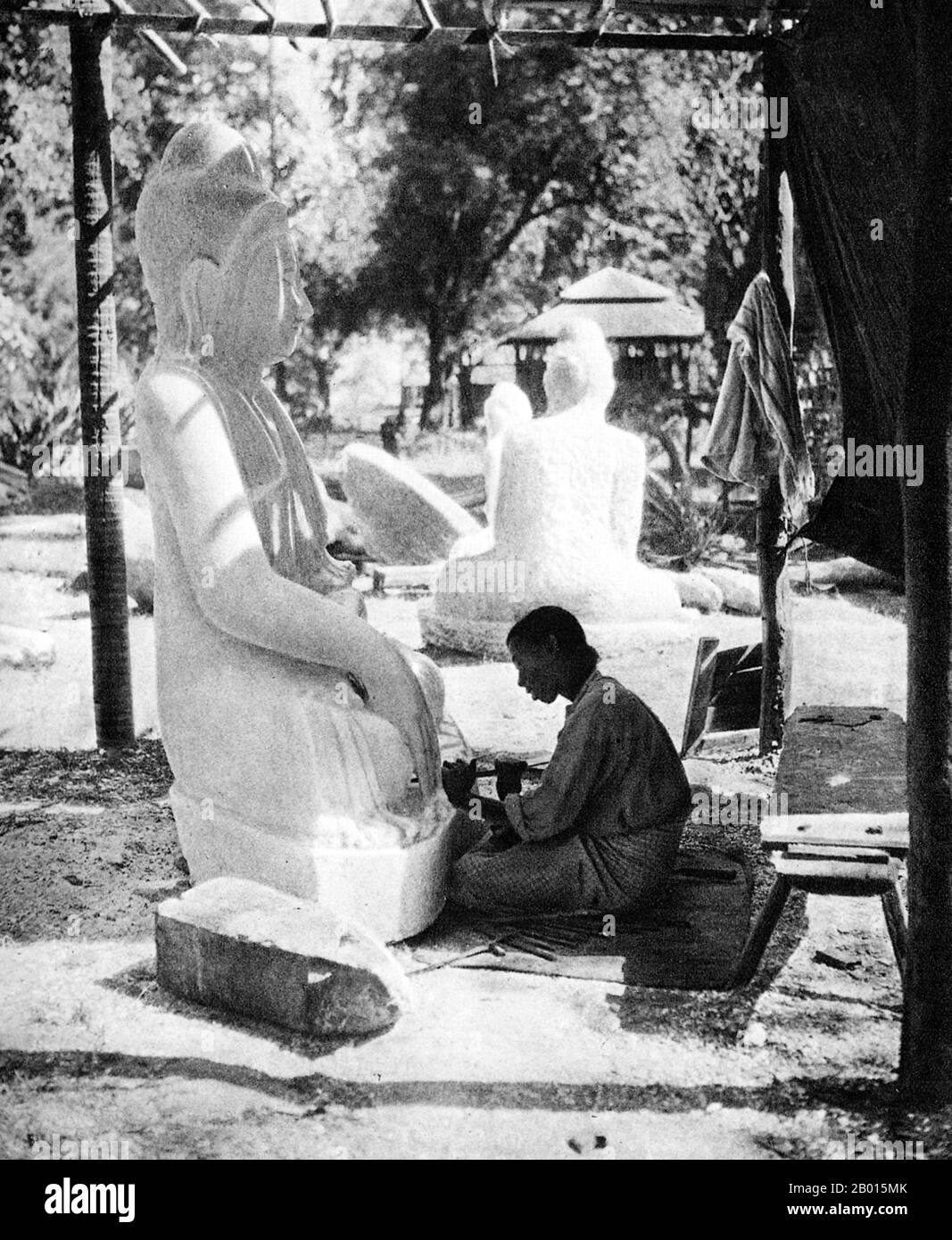 Burma/Myanmar: A sculptor carves a Buddha statue from marble in Prome, lower Burma, c. 1920s.  Legend attributes the first Buddhist doctrine in Burma to 228 BCE when Sohn Uttar Sthavira, one of the royal monks to Emperor Ashoka the Great of India, came to the country with other monks and sacred texts. However, the era of Buddhism truly began in the 11th century after King Anawrahta of Pagan (Bagan) was converted to Theravada Buddhism. Today, 89% of the population of Burma is Theravada Buddhist.  Prome, renamed Pyay, is a town in Pegu (Bago) Division in lower Burma, located on the Irrawaddy. Stock Photo