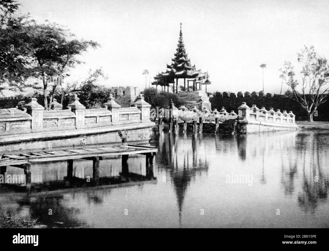 Burma/Myanmar: Bridge across the moat to the Royal City in Mandalay, central Burma, c. 1920s.  Mandalay Palace was constructed between 1857 and 1859 as part of King Mindon's new royal capital city of Mandalay, in fulfillment of a Buddhist prophecy that a religious centre would be built at the foot of Mandalay Hill.  In 1861 the court was transferred to the newly built city from the previous capital of Amarapura. The plan of Mandalay Palace largely follows the traditional Burmese palace design, inside a walled fort surrounded by a moat. The palace itself is at the centre of the citadel. Stock Photo